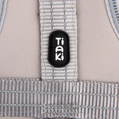 Close-up van een grijze riem met Tiaki-logo op zwart kunststof onderdeel.