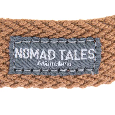 Nomad Tales München. Ετικέτα μάρκας σε καφέ πλεκτό υλικό.