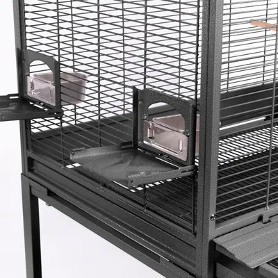 Vogelkäfig aus Metall mit herausnehmbaren Futterstationen und Gittertüren. Zwei Edelstahl-Futterschalen sichtbar.