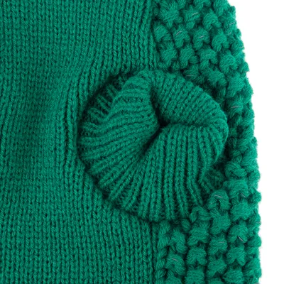 Close-up of green knitted material with various textures, including smooth and chunky patterns.