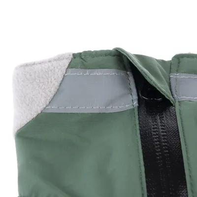 Közelkép zöld textil anyagról szürke polár béléssel, fényvisszaverő csíkokkal és fekete cipzárral.