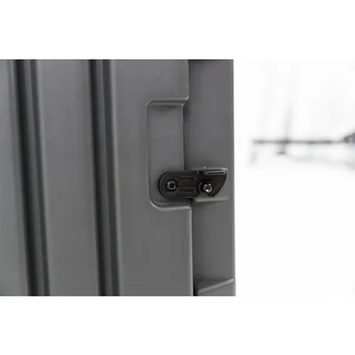 Zbliżenie na metalowy zawias lub zatrzask w szarej ramie, widoczne dwa czarne wkręty mocujące element.