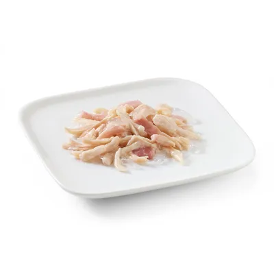 Close-up of shredded chicken meat on a white plate, presented as a product image for pet food.