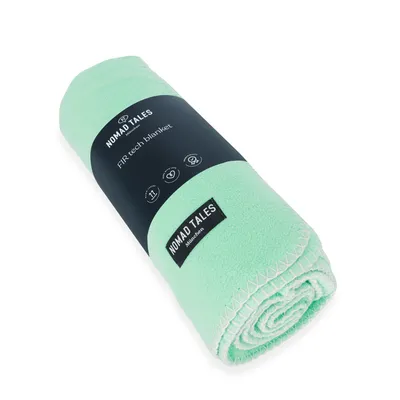 Nomad Tales FIR-tech blanket, mintgrün, mit Label und Icons für Komfort, Wärme und Pflegehinweise.