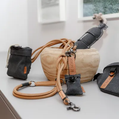 Ensemble d’accessoires pour chien en cuir et tissu gris, comprenant laisse, pochette et distributeur de sacs, étiquettes visibles avec la marque BE NORDIC.