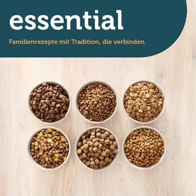 essential. Familienrezepte mit Tradition, die verbinden. Sechs Schalen mit verschiedenen Sorten Trockenfutter auf hellem Holzuntergrund.