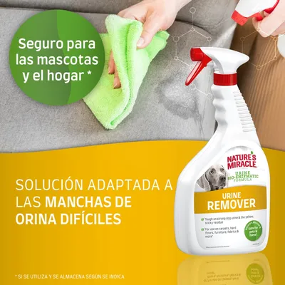 Spray Nature's Miracle Urine Remover, texto visible: 'Seguro para las mascotas y el hogar', 'Solución adaptada a las manchas de orina difíciles'. Mano limpiando sofá con paño verde.