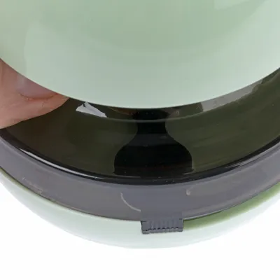Close-up of a hand opening or closing a round container with a transparent lid and a small latch mechanism.