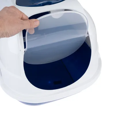 Hand öffnet transparente Klappe einer weissen Katzentoilette mit blauem Innenraum.