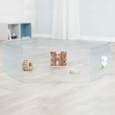 Metall-Freigehege mit Gitterwänden, ausgestattet mit Holzhaus, Heuball, Trinkflasche und Futternapf auf hellem Laminatboden.