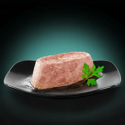 Portion of wet food on a black plate, garnished with a fresh parsley leaf.