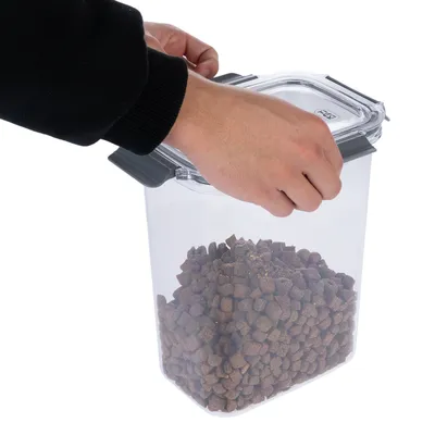 Hand opent transparante container met droogvoer, geschikt voor het bewaren van dierenvoeding.