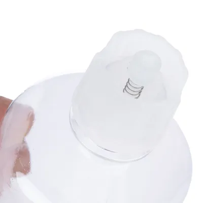 Primer plano de una botella transparente con mecanismo de resorte en la tapa, adecuada para dosificación precisa de líquidos.