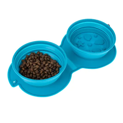 Gamelle double pliable en silicone bleu, une coupelle remplie de croquettes, l’autre vide avec motifs en relief au fond. Convient pour nourriture et eau.