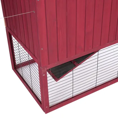 Roter Holzstall mit Gitterwänden und schräger Klappe, geeignet für Kleintiere. Detailansicht der unteren Hälfte des Stalls.