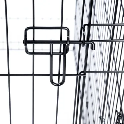 Vue détaillée d'une fermeture en métal noir sur une cage grillagée, montrant le verrouillage sécurisé du mécanisme de porte.