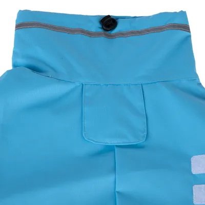 Vue rapprochée d’un vêtement bleu pour animal avec bande réfléchissante grise, bouton noir et poche sur le devant. Matière textile visible.