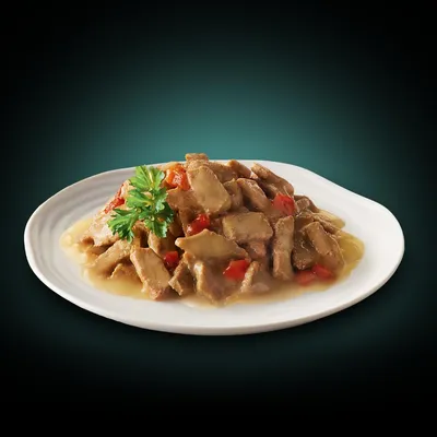 Chunks of meat in gravy with visible red vegetable pieces, served on a white plate and garnished with parsley.