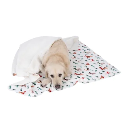 Manta branca sobre uma base estampada com motivos de Natal, incluindo pinheiros e animais.