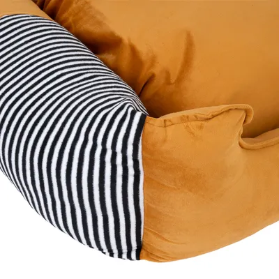 Detailansicht eines orangefarbenen Haustierbetts mit schwarz-weiss gestreiftem Stoff an der Seite.