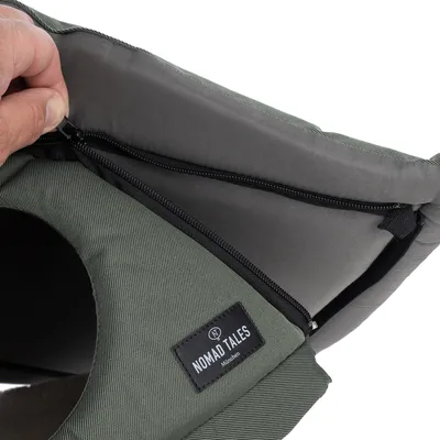 Primer plano de una funda de tela verde con cremallera y etiqueta 'Nomad Tales München'.