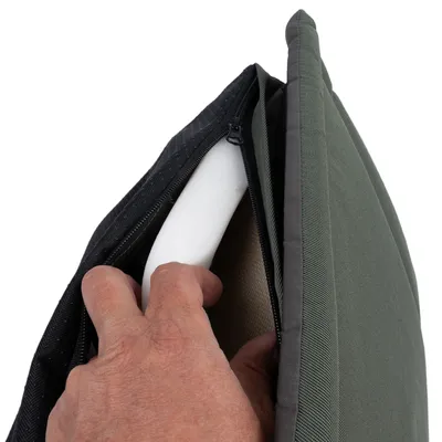 Primer plano de una mano abriendo la cremallera de un cojín verde y mostrando el relleno de espuma blanca.