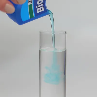 Blaues Flüssigprodukt wird aus einer Verpackung mit der Aufschrift 'Bio' in ein Glasgefäss gegossen.