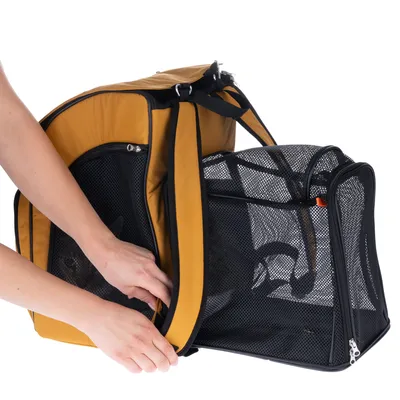 Sac de transport pour animaux en tissu jaune et noir, parties en maille noire, une personne ouvre la fermeture éclair latérale. Animal visible à l’intérieur du sac.
