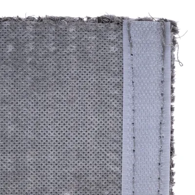 Close-up van grijze stof met antislip onderkant en verstevigde rand.