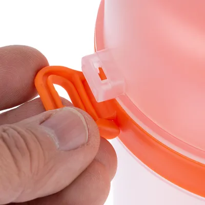 Nahaufnahme eines orangefarbenen Verschlussclips an einem Behälter, der von einer Hand geöffnet wird.