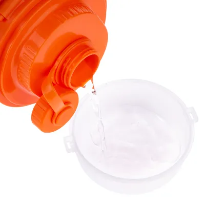 Oranger Behälter mit Ausgiesser, aus dem Wasser in eine weisse Schale gegossen wird.