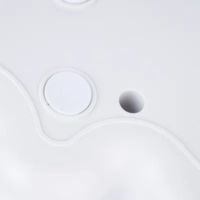 Nahaufnahme einer weissen Kunststoffoberfläche mit runden Vertiefungen und Löchern, möglicherweise Teil eines Spielzeugs oder Zubehörs.