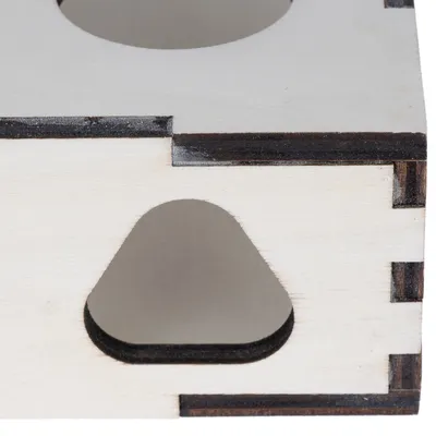 Détail d’un cube en bois clair avec ouverture triangulaire et assemblage à tenons visibles. Aucun texte ou marque apparente.
