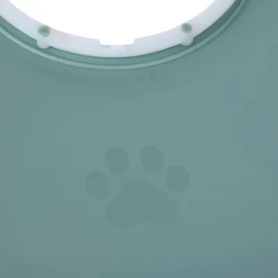 Green plastic surface with embossed paw print and round cut-out at the top.