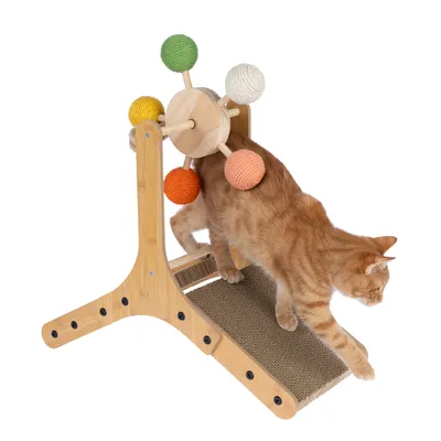 Chat roux sur un arbre à chat en bois avec rampe en carton et roue ornée de boules colorées en corde (vert, blanc, jaune, orange).