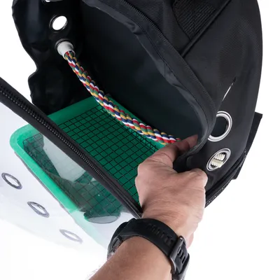 Intérieur d’un sac de transport noir avec paroi transparente, grille verte au fond, corde multicolore fixée à l’intérieur et œillets métalliques visibles sur le côté.