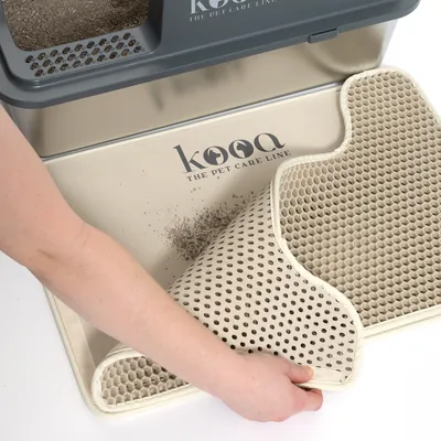 kooa podložka pod mačacie stelivo s včelími plástmi, ruka zdvíha podložku na čistenie. Viditeľné logo 'kooa The Pet Care Line'.
