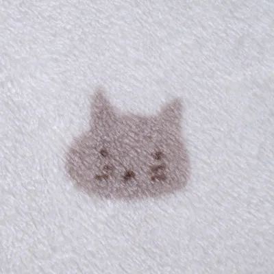 Motif tête de chat marron sur tissu polaire blanc, matière douce et duveteuse visible en gros plan.