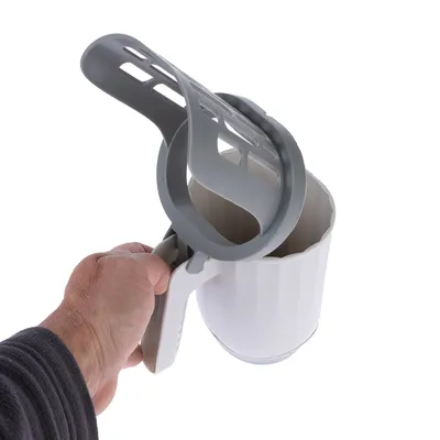 Mano sostiene vaso medidor blanco con asa gris y tapa colador, apto para dosificar alimento para mascotas u otros materiales.