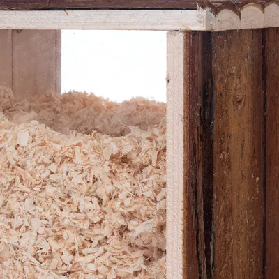 Holzbehälter mit transparentem Fenster, gefüllt mit hellen Holzspänen. Sichtbar sind die Struktur der Späne und die Holzmaserung des Behälters.
