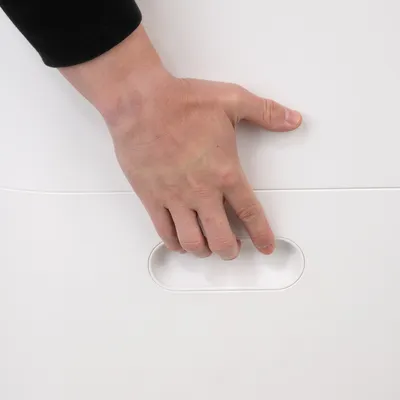 Hand reaching into an integrated handle of a white container, showing easy handling and transport option.