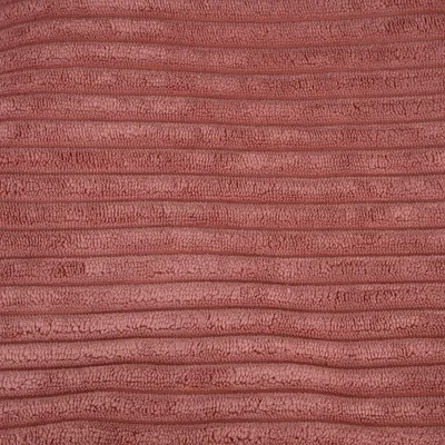 Gros plan sur une surface en tissu rose à texture côtelée, matière pelucheuse visible. Aucun texte ou marque apparente.