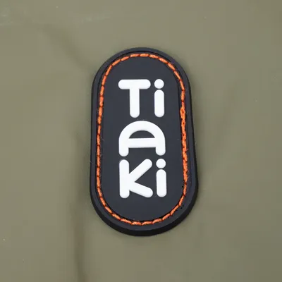 Tiaki. Markenlogo mit weisser Schrift auf schwarzem Hintergrund und orangefarbener Umrandung.