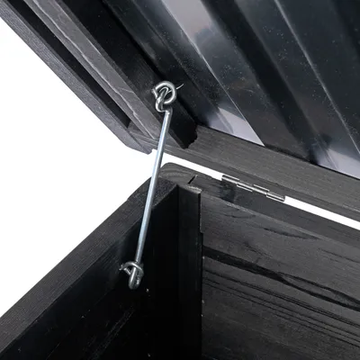 Detailansicht eines schwarzen Holzdeckels mit Metallstütze und Scharnieren, die den Deckel offen halten.