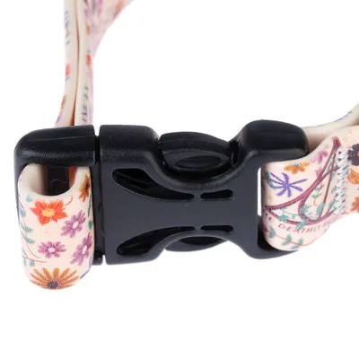 Nahaufnahme eines schwarzen Kunststoffverschlusses an einem Halsband mit floralem Muster in verschiedenen Farben.