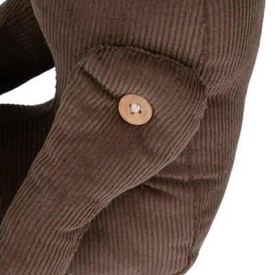 Közelkép egy barna textil játékfiguráról, gombbal ízületi kapcsolathoz.