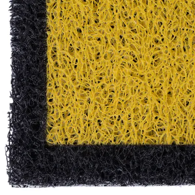 Nahaufnahme einer gelben und schwarzen Matte mit strukturierter Oberfläche aus Kunststofffasern.