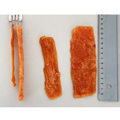 Trei bucăți de carne uscată lângă o furculiță și o riglă pentru comparație de dimensiune, lungime până la 14 cm.