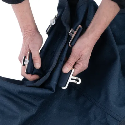 Hände zeigen die Befestigung von Metallclips an einem dunkelblauen Stoff, geeignet für Gurte oder Verschlüsse.