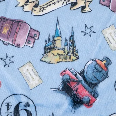 Illustrazioni su tessuto blu: castello, treno rosso, valigia, stelle e pergamene. Design ispirato a temi magici.